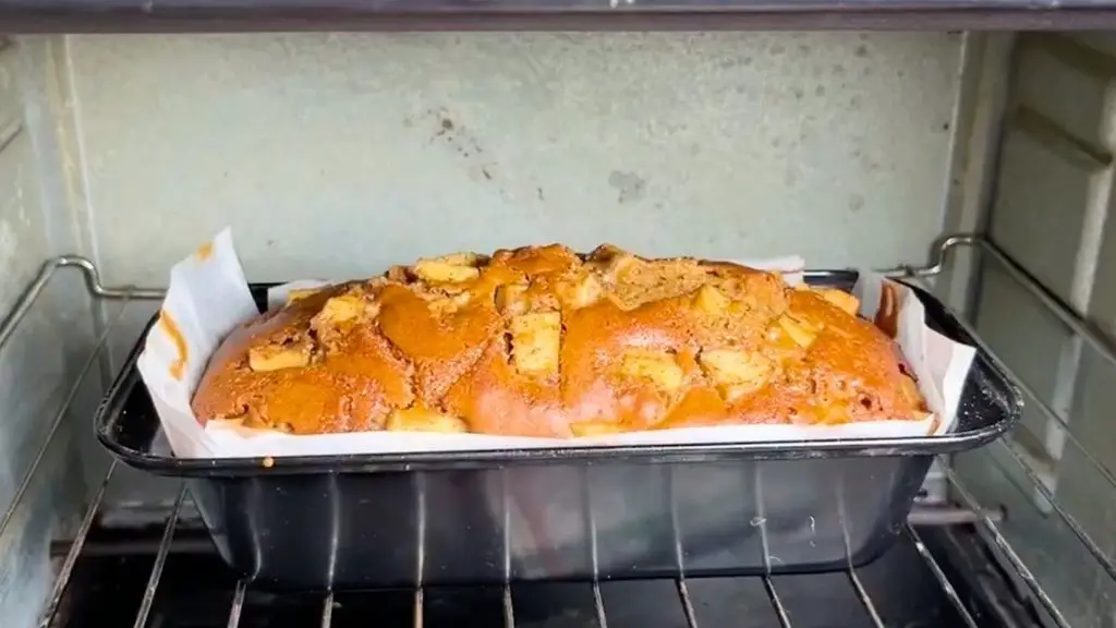 Moist apple cinnamon cake baking in the oven until risen and golden brown with tender cinnamon apples on top.