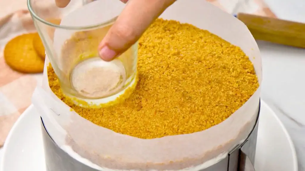 Pressing the final biscuit crust into place on the triple layer cheesecake.
