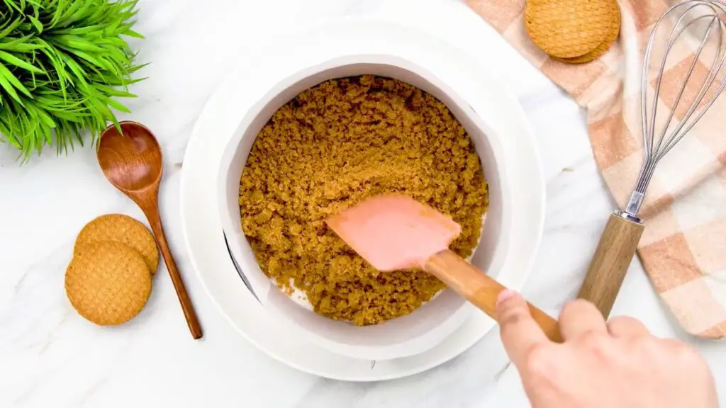 Triple layer cheesecake biscuit crumbs being divided evenly to create the three crust layers.
