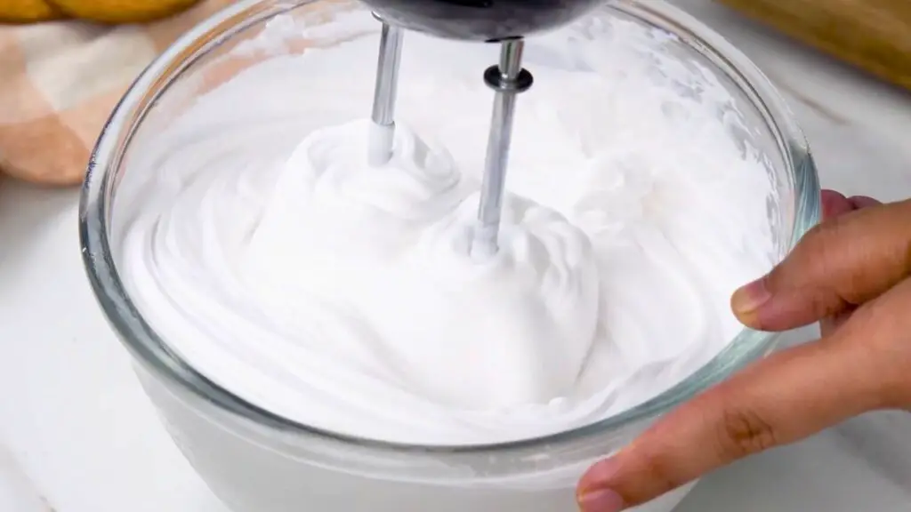 Whipping cold cream to firm peaks for the best cheesecake recipe.
