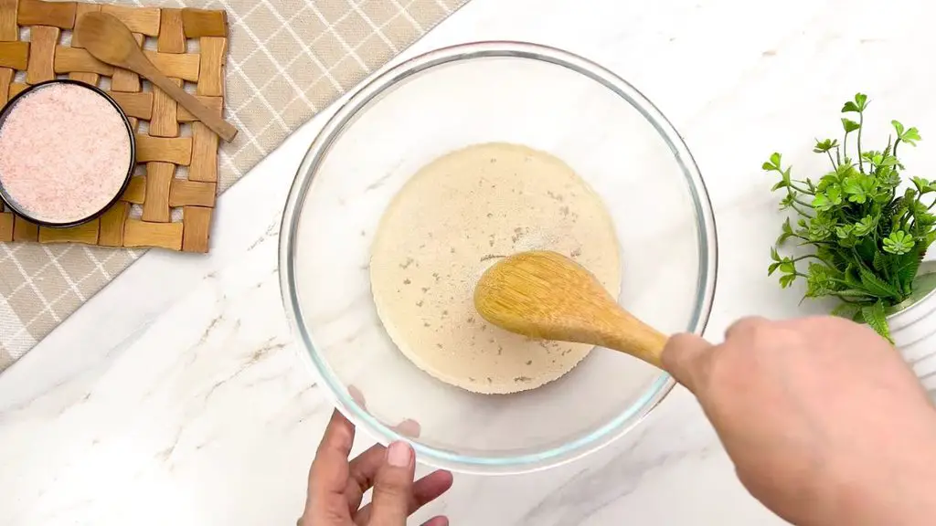 Active dry yeast being stirred into lukewarm water to start the yeast for homemade air fryer bread.