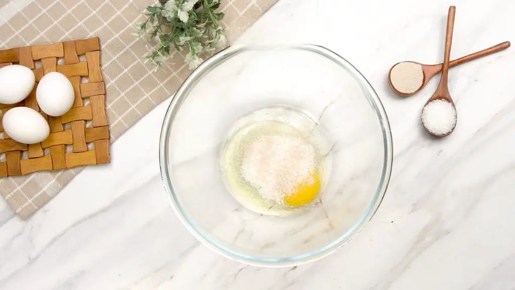 Egg, sugar, dry yeast, and lukewarm milk in a mixing bowl for making air fryer brioche buns.