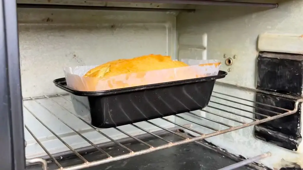 Golden lemon cake baking in a loaf pan in the oven.