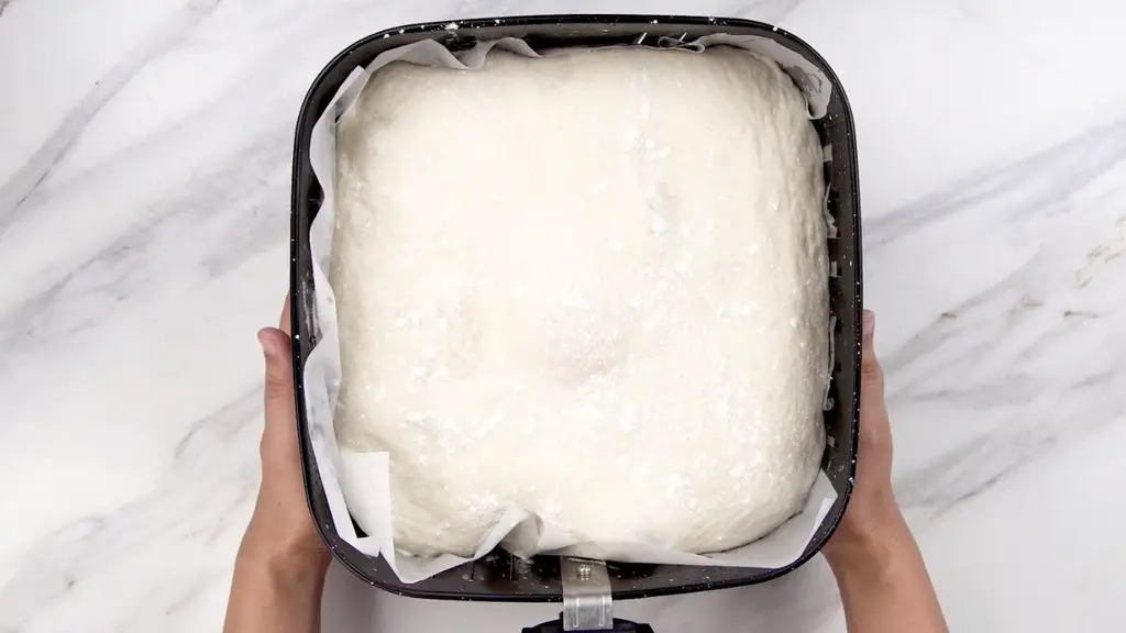 Large risen bread dough filling a parchment-lined air fryer basket after its second rise.