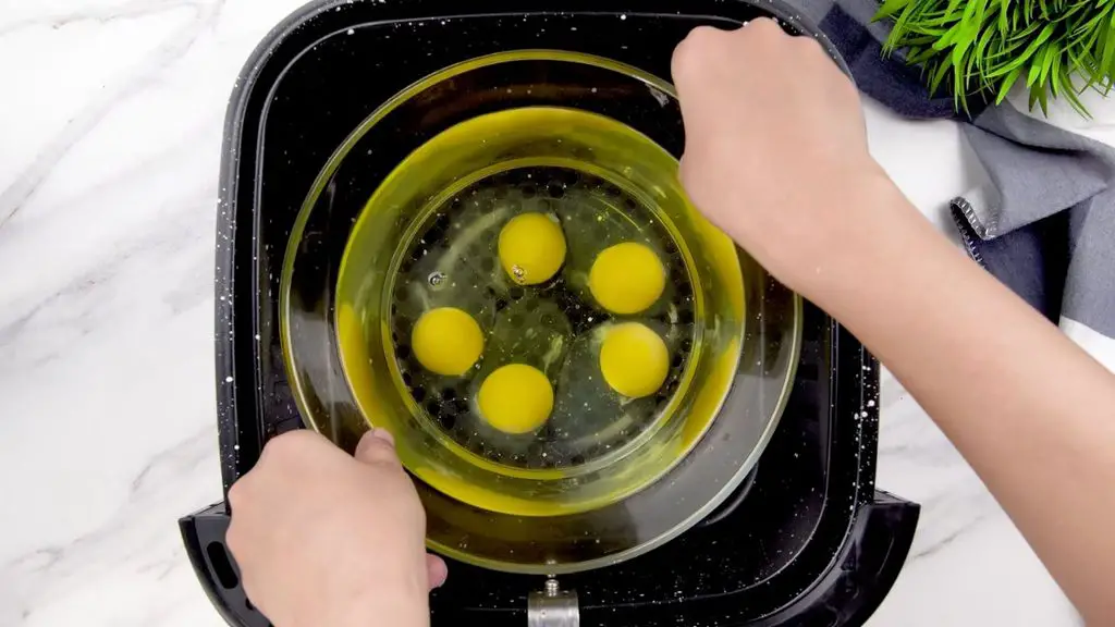 Poached eggs cooking in a glass bowl inside an air fryer at 340°F (170°C).