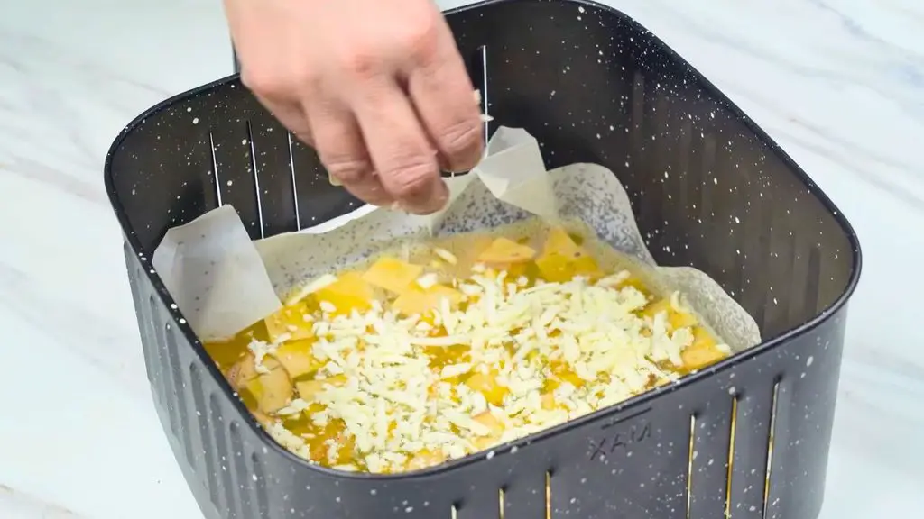 Shredded cheese being added over the ham and eggs for an easy air fryer omelette.