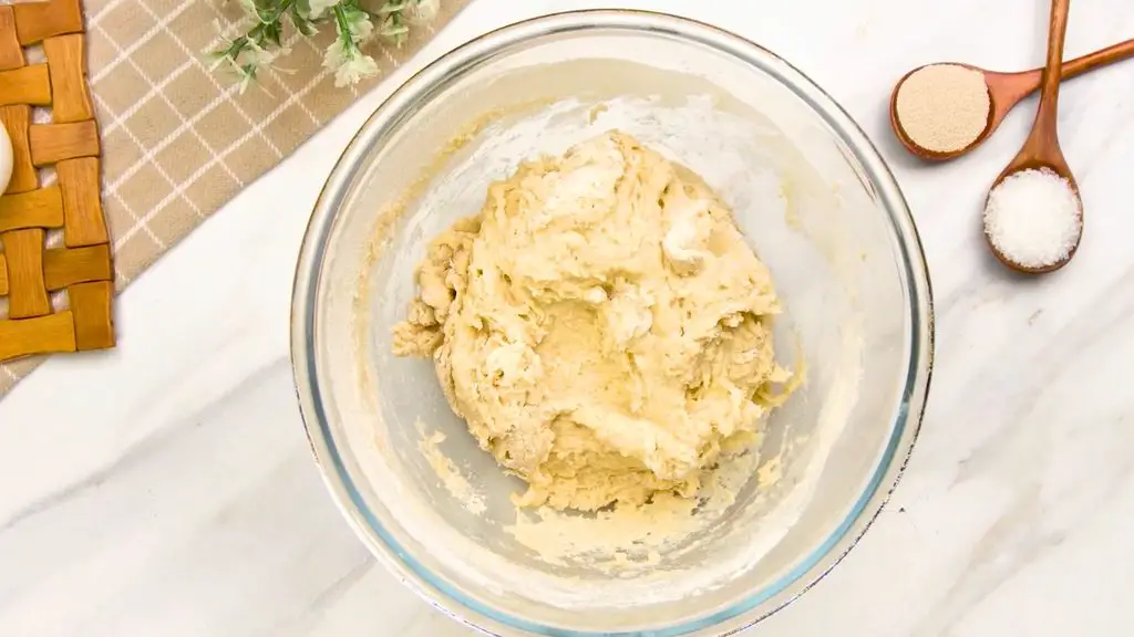 Soft brioche dough mixed with flour and salt in a glass bowl for air fryer brioche buns.