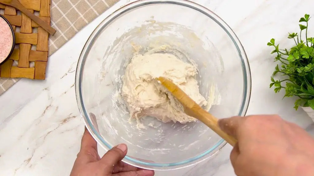 Sticky no-knead dough being mixed for this easy air fryer bread recipe before it is left to rise.