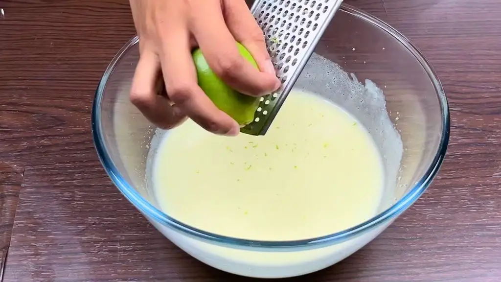 Zesting fresh lemon into cake batter for a homemade lemon cake recipe.
