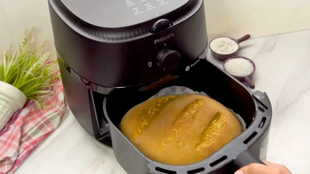 Air fryer milk bread baked until golden brown, topped with sesame seeds and resting in a parchment-lined air fryer basket.