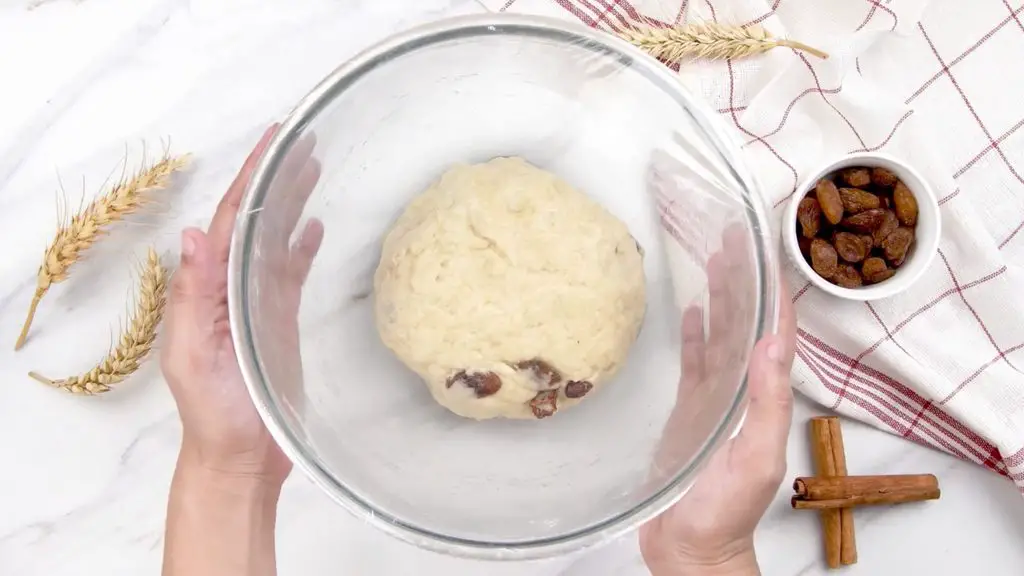 Cinnamon swirl raisin bread dough resting in a glass bowl before rising.