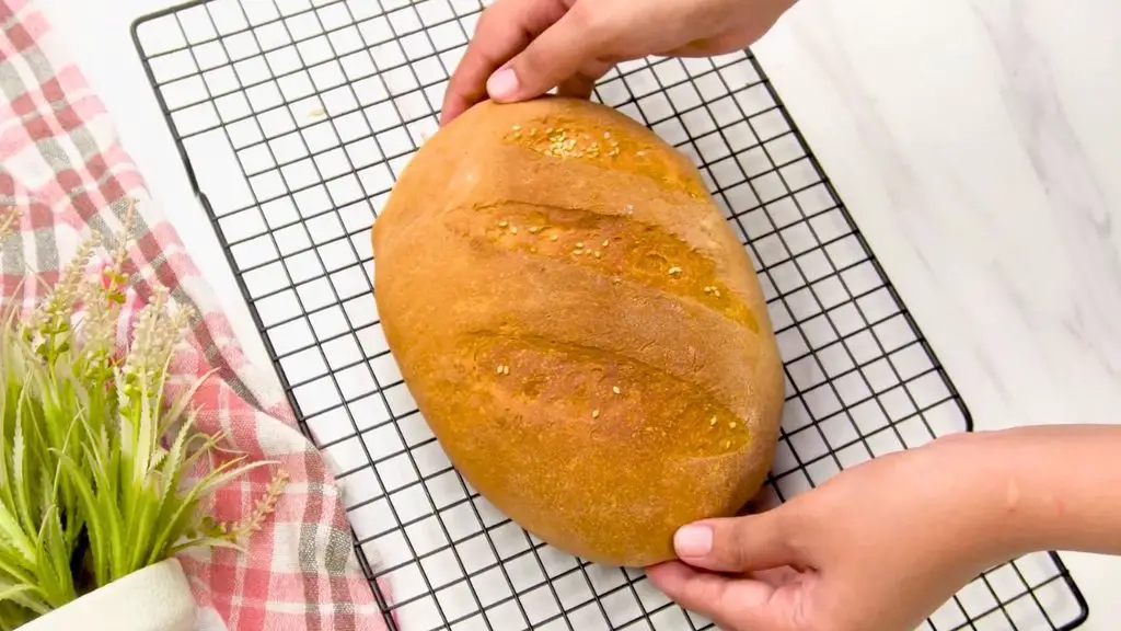 Freshly baked air fryer milk bread with a golden brown crust, sesame seed topping, and diagonal cuts, cooling on a wire rack.
