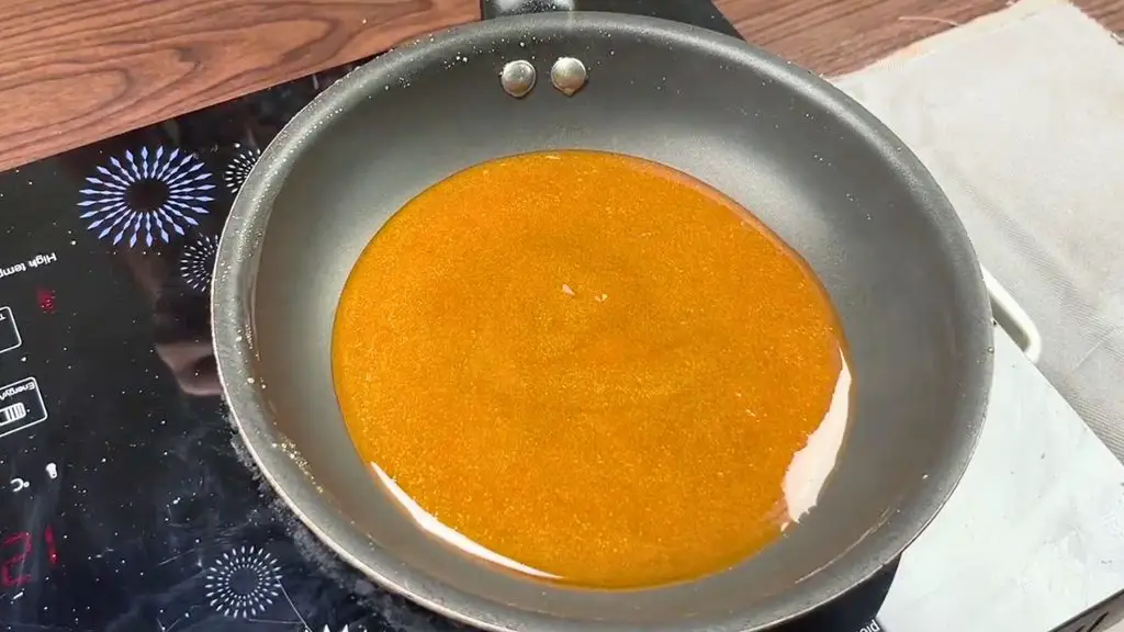 Golden caramel syrup cooking in a pan for a carrot date cake recipe.
