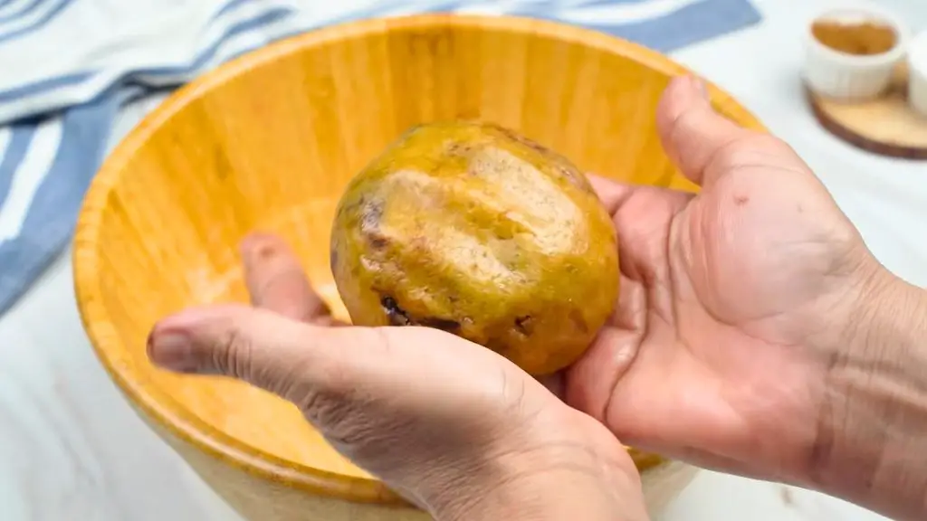 Shaping brown butter chocolate chip cookie dough into a thick ball by hand, with chocolate pieces tucked inside before baking.