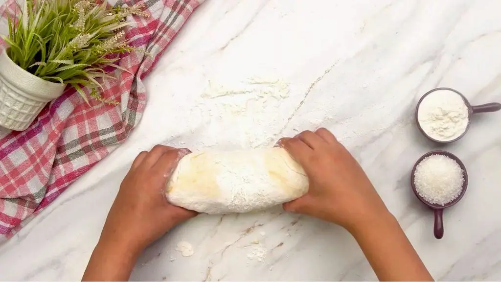 Shaping soft dough into a loaf on a lightly floured surface for an air fryer bread recipe.