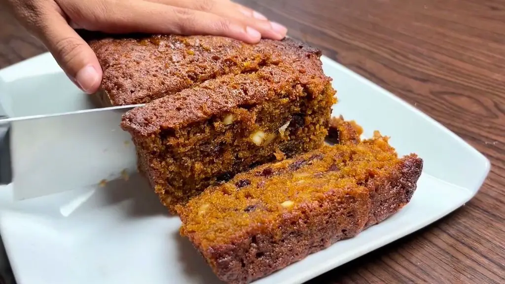 Slicing the best carrot and dates cake, showing the moist center with dates and cashews