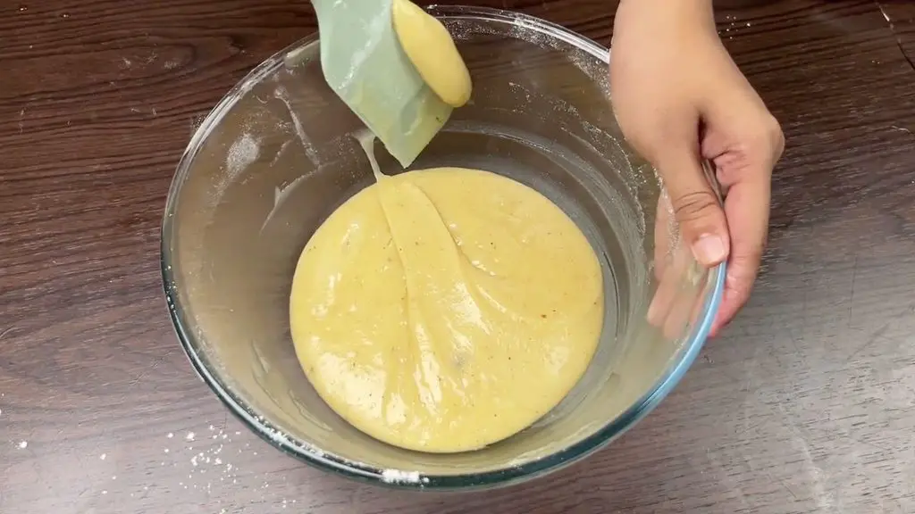 Smooth carrot date cake batter mixed with flour and warm spices in a glass bowl.