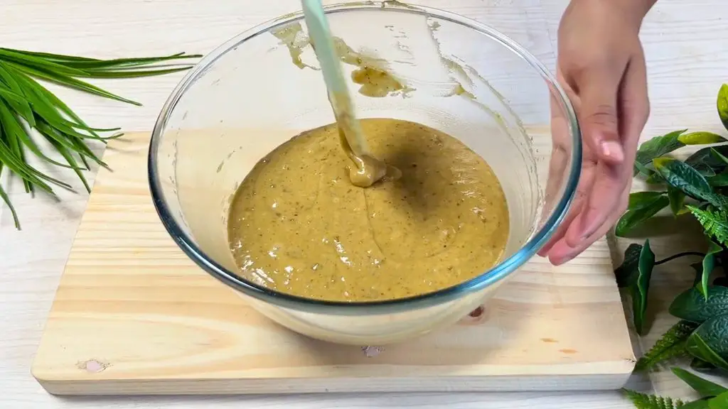 Sticky apple toffee cake batter being mixed with a spatula in a glass bowl after adding the wet ingredients.