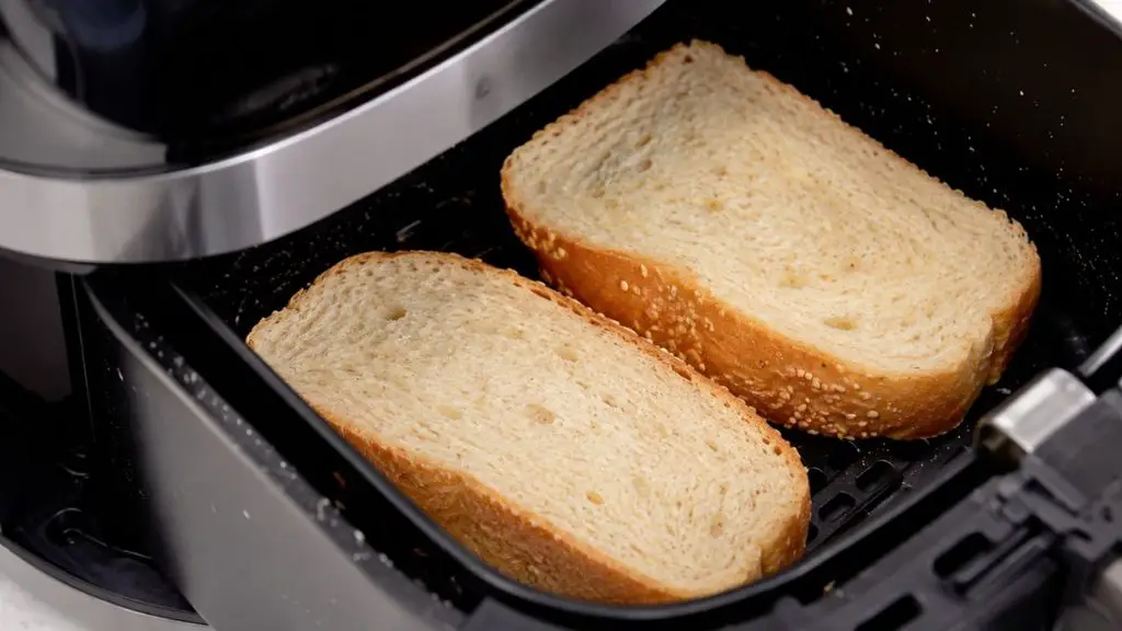 Two slices of air fryer milk bread placed in an air fryer basket for reheating.